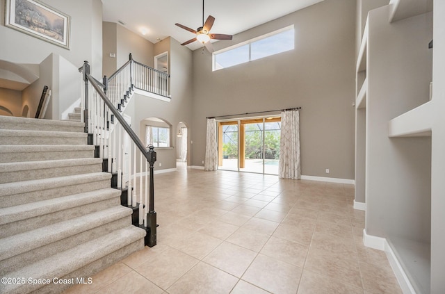 tiled entryway with ceiling fan and a high ceiling