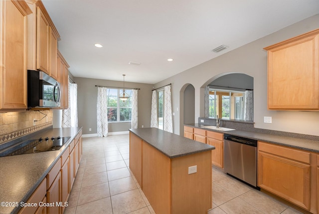 kitchen featuring sink, light tile patterned flooring, a kitchen island, and appliances with stainless steel finishes