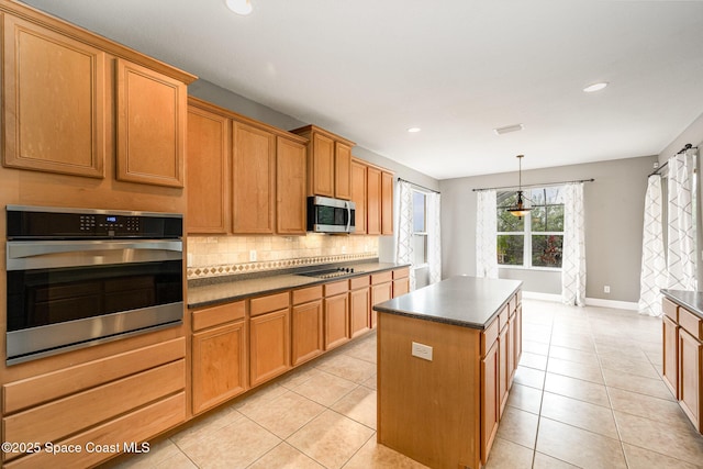 kitchen with appliances with stainless steel finishes, a center island, decorative light fixtures, backsplash, and light tile patterned floors