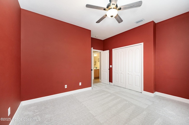 unfurnished bedroom featuring ceiling fan, light colored carpet, and a closet