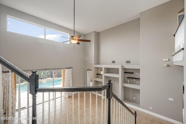 staircase featuring ceiling fan, a high ceiling, built in shelves, and tile patterned flooring