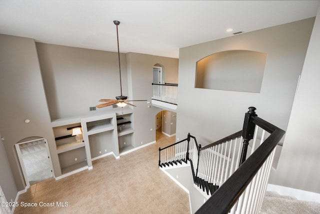 stairs featuring ceiling fan, a high ceiling, and built in shelves