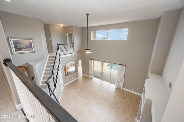 stairs with ceiling fan and a high ceiling