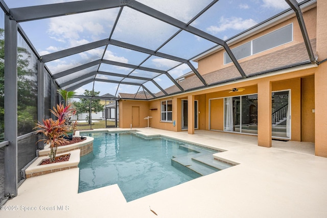 view of pool with a patio, glass enclosure, and ceiling fan