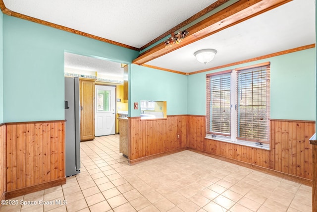 spare room featuring light tile patterned floors, ornamental molding, a textured ceiling, and wood walls