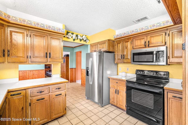 kitchen with light tile patterned floors, stainless steel appliances, and a textured ceiling