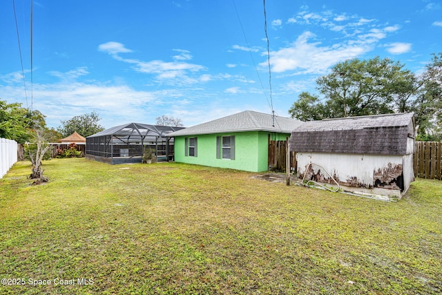 back of property featuring a yard and glass enclosure