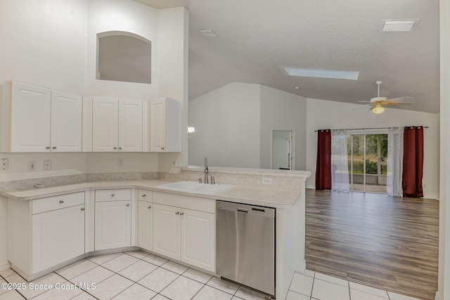 kitchen with kitchen peninsula, dishwasher, a skylight, white cabinetry, and sink