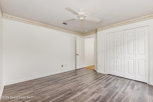 unfurnished bedroom featuring ceiling fan, a closet, a textured ceiling, and wood-type flooring