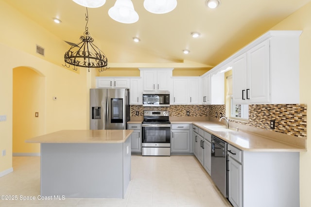 kitchen with a center island, decorative light fixtures, tasteful backsplash, appliances with stainless steel finishes, and sink