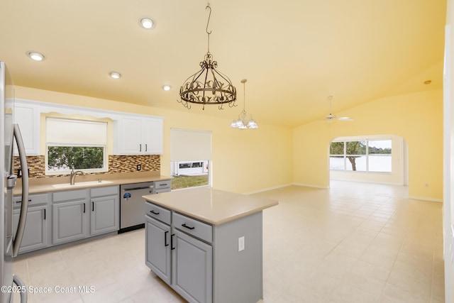 kitchen with white cabinets, vaulted ceiling, stainless steel appliances, sink, and ceiling fan with notable chandelier