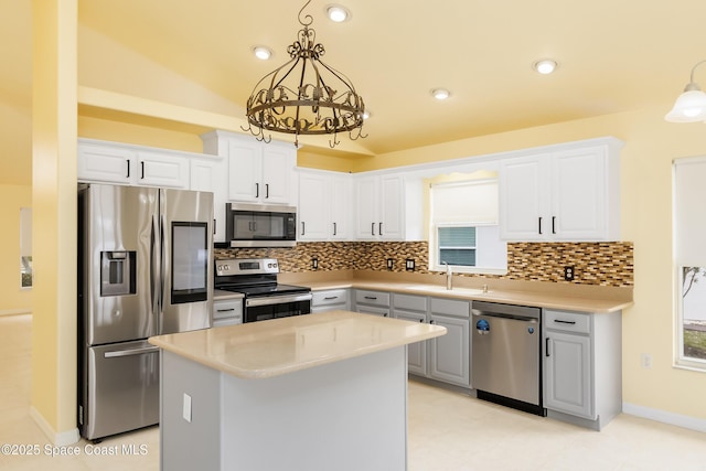 kitchen featuring white cabinets, a center island, hanging light fixtures, and appliances with stainless steel finishes