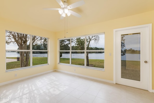 unfurnished sunroom featuring ceiling fan and a water view