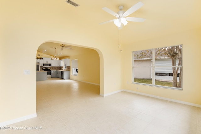 empty room featuring vaulted ceiling, ceiling fan, and light tile patterned floors