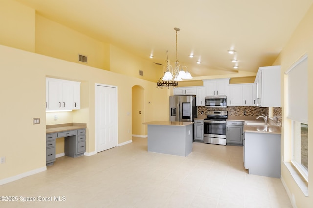 kitchen with hanging light fixtures, a center island, stainless steel appliances, an inviting chandelier, and backsplash