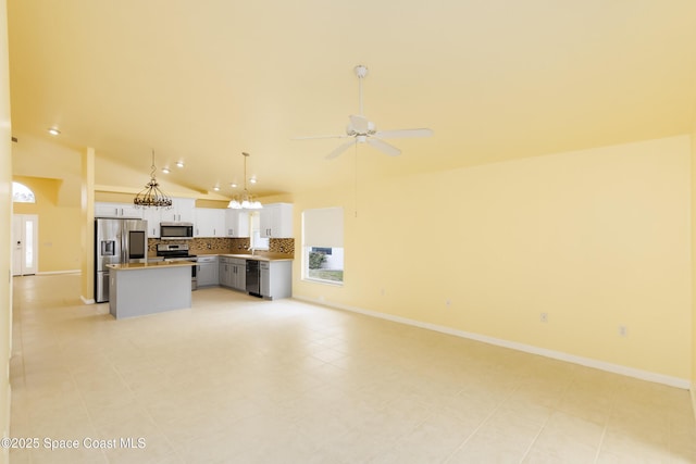 kitchen with appliances with stainless steel finishes, ceiling fan, a kitchen island, white cabinets, and decorative light fixtures