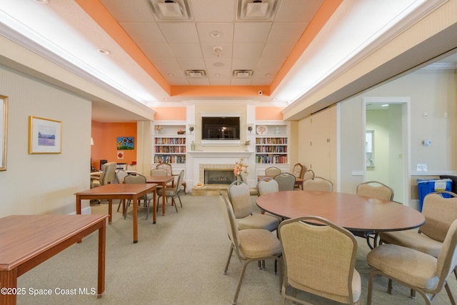 dining room featuring a paneled ceiling, a raised ceiling, light carpet, and built in shelves