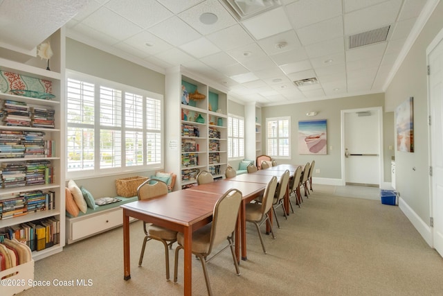 dining area featuring light colored carpet, crown molding, and a drop ceiling