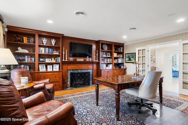 home office featuring french doors, light wood-type flooring, crown molding, and a fireplace