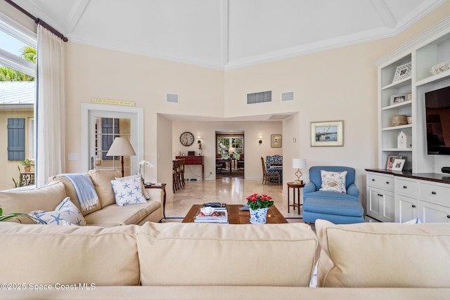 living room featuring a towering ceiling and crown molding