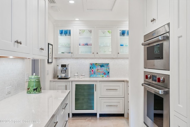 kitchen featuring stainless steel double oven, white cabinets, and wine cooler