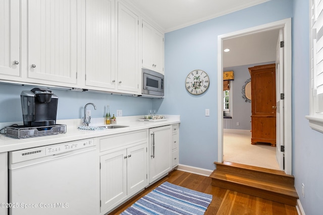 kitchen featuring white dishwasher, dark hardwood / wood-style flooring, stainless steel microwave, sink, and white cabinetry