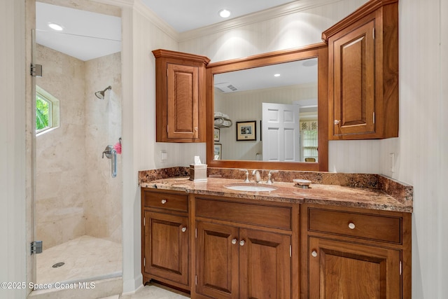 bathroom featuring vanity, a shower with shower door, and crown molding