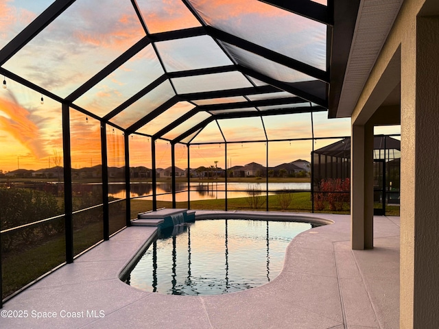 pool at dusk featuring a water view, a lanai, and a patio