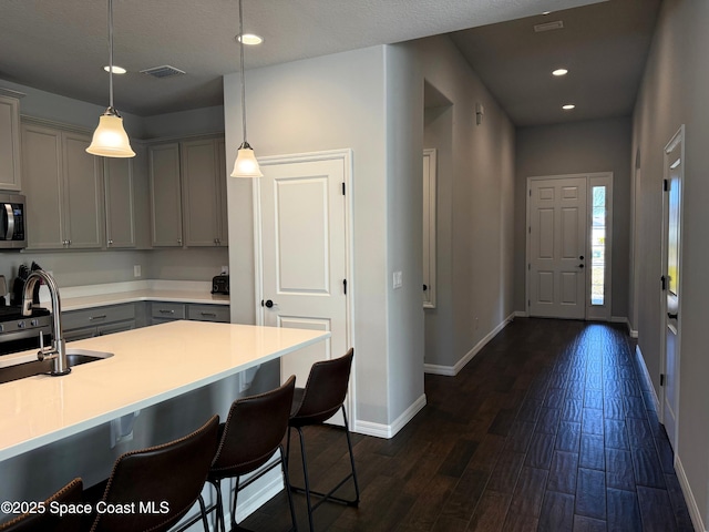 kitchen featuring a kitchen bar, sink, gray cabinetry, dark hardwood / wood-style floors, and pendant lighting