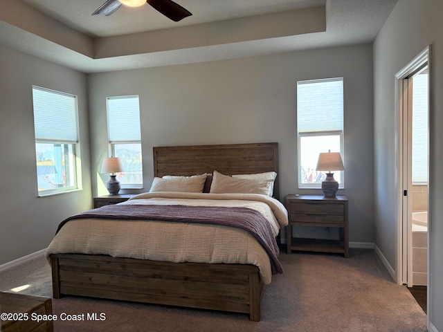 bedroom featuring dark carpet and a tray ceiling