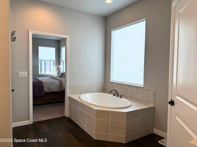 bathroom featuring hardwood / wood-style floors and tiled tub