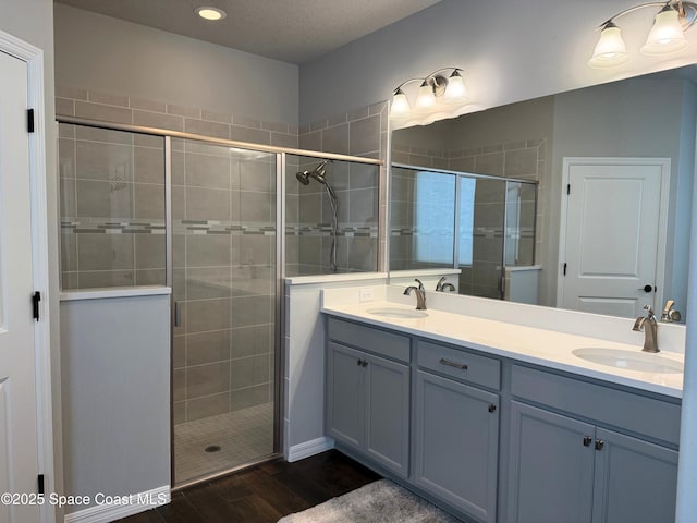 bathroom featuring wood-type flooring, a shower with door, and vanity