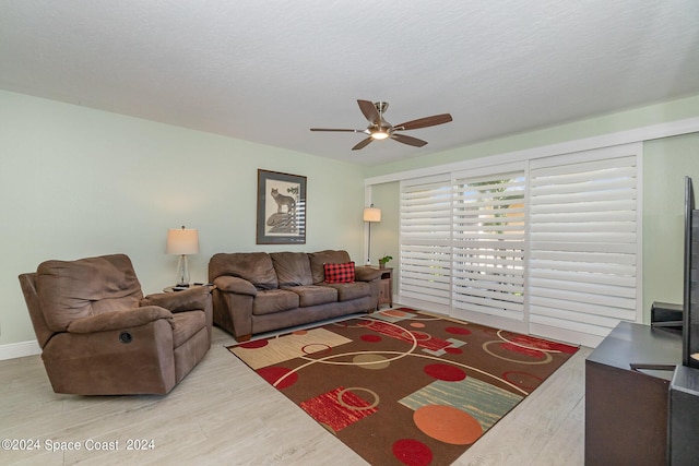 living room with hardwood / wood-style flooring, a textured ceiling, and ceiling fan