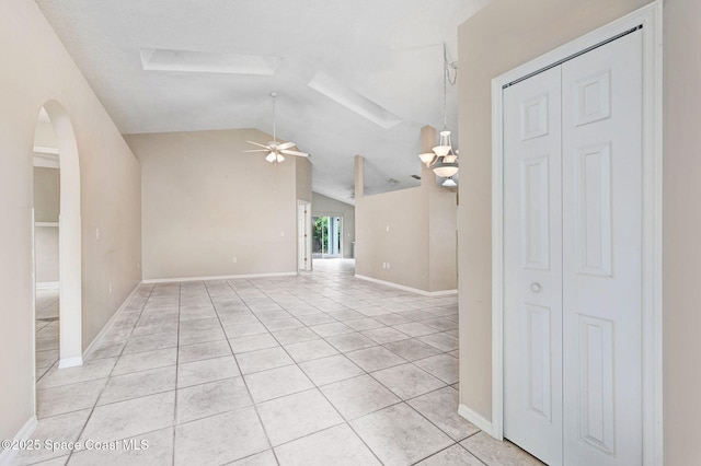 unfurnished living room with ceiling fan, light tile patterned flooring, and vaulted ceiling with skylight