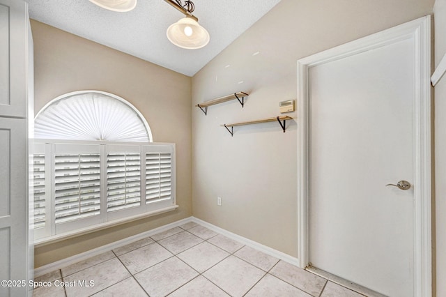 interior space with a textured ceiling, lofted ceiling, and light tile patterned floors