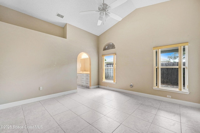 tiled spare room featuring ceiling fan, high vaulted ceiling, plenty of natural light, and a textured ceiling