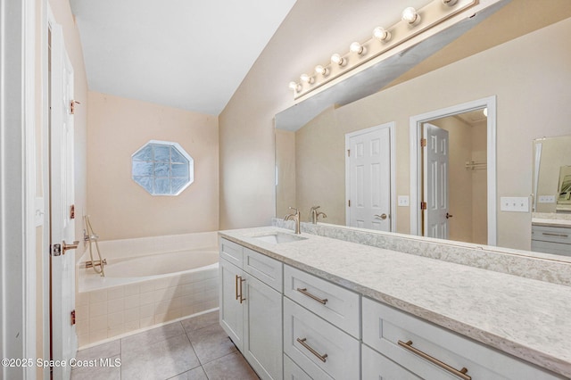 bathroom with lofted ceiling, vanity, tile patterned floors, and tiled bath