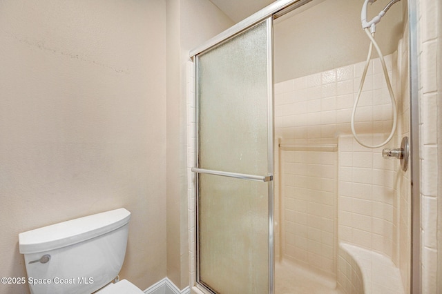 bathroom featuring toilet and a shower with door