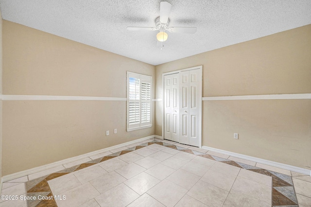 unfurnished bedroom featuring ceiling fan, a closet, light tile patterned flooring, and a textured ceiling