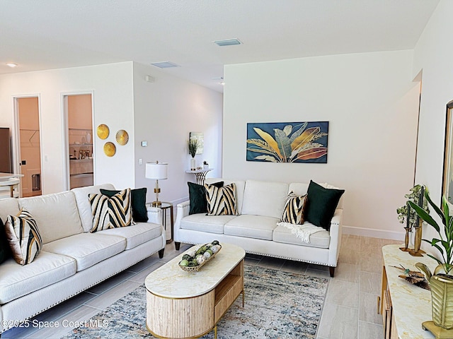 living room with light tile patterned floors, baseboards, and visible vents