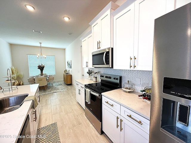 kitchen featuring visible vents, appliances with stainless steel finishes, tasteful backsplash, white cabinets, and a chandelier