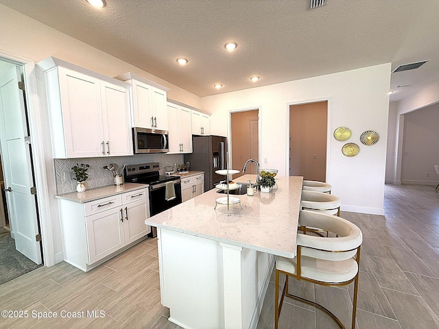 kitchen with a sink, appliances with stainless steel finishes, a breakfast bar, and wood tiled floor