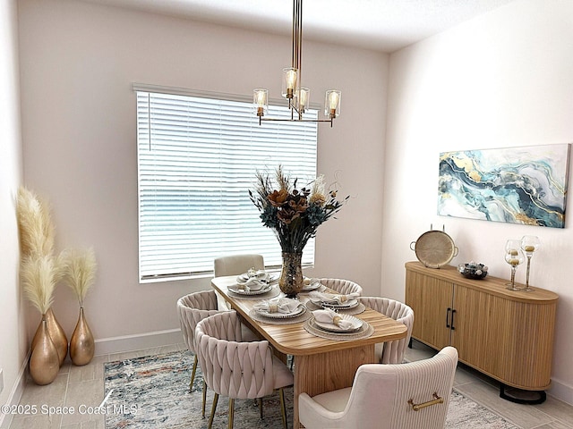 dining area with light tile patterned floors, baseboards, and a notable chandelier