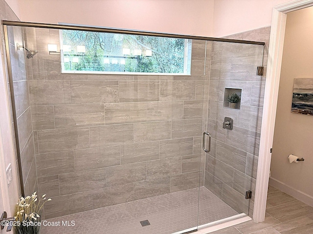 bathroom featuring baseboards and a shower stall