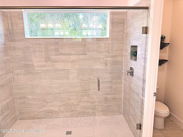 bathroom featuring tile patterned flooring, baseboards, toilet, and a shower stall