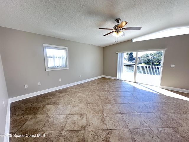 unfurnished room with baseboards, lofted ceiling, a textured ceiling, and a ceiling fan