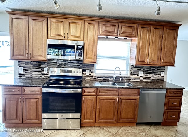 kitchen featuring a sink, dark stone countertops, brown cabinets, and stainless steel appliances