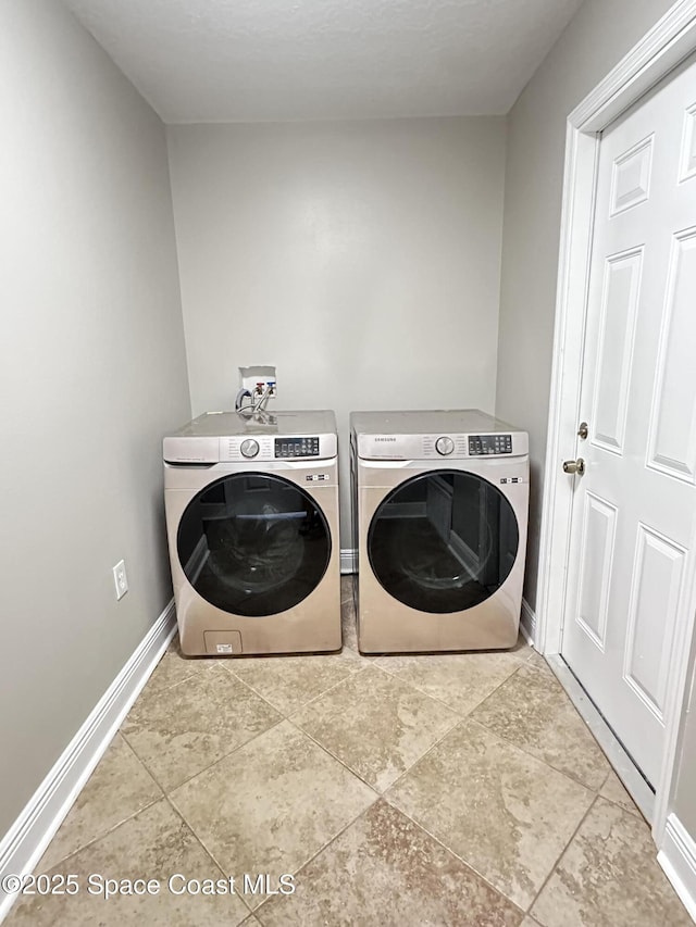 clothes washing area featuring tile patterned flooring, laundry area, baseboards, and separate washer and dryer