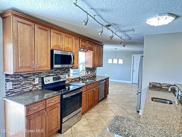 kitchen with a sink, stainless steel appliances, brown cabinetry, and light tile patterned floors