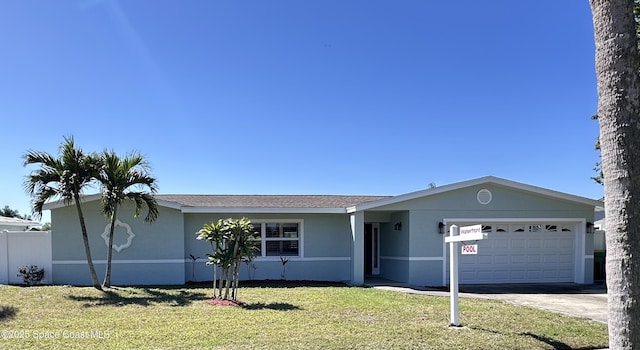 view of front of home featuring fence, a front yard, stucco siding, a garage, and driveway